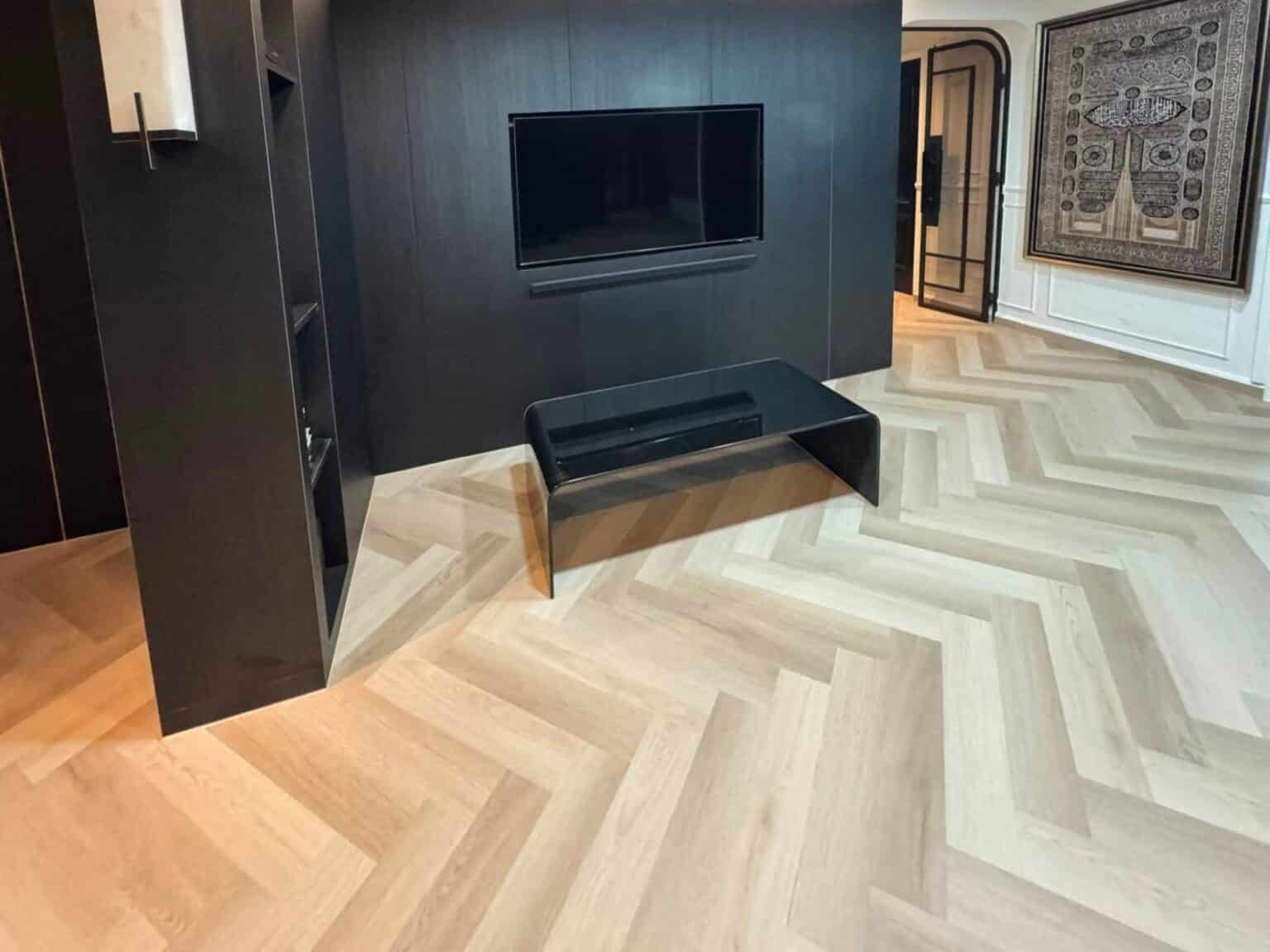 Carrera Oak herringbone vinyl flooring in a living room with a dark TV feature wall