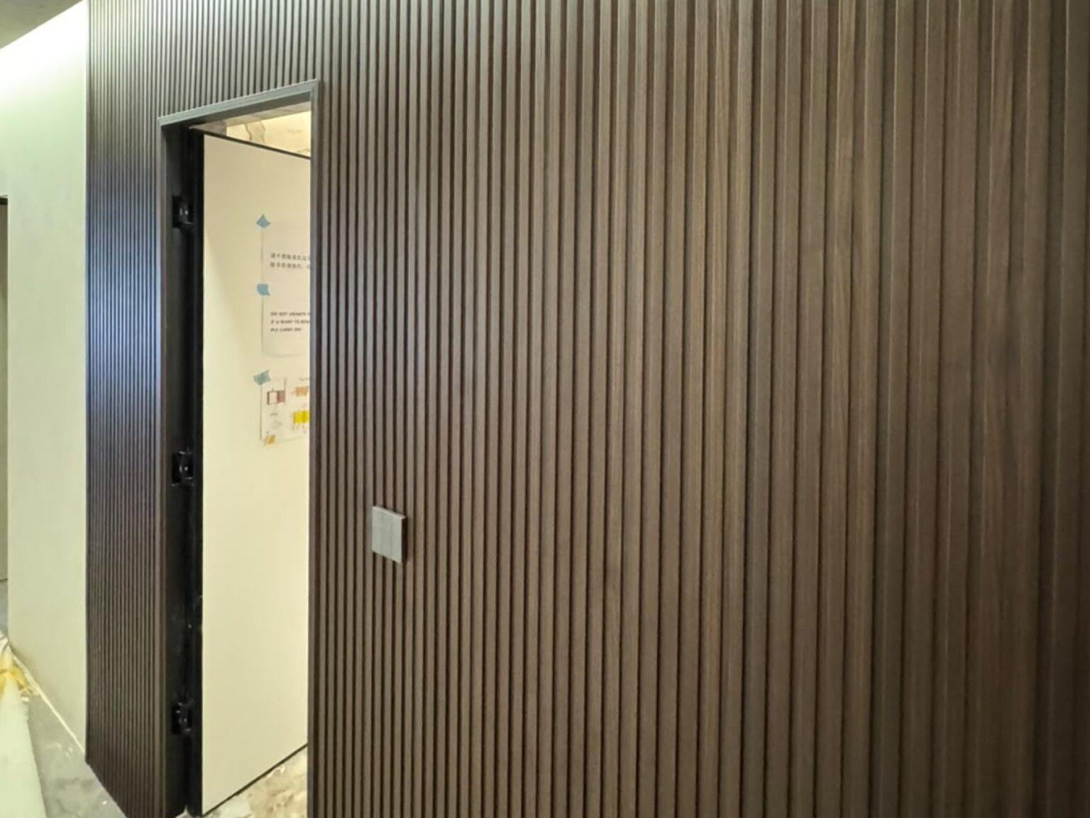 Dark wood fluted panels wrapping a corridor wall with a concealed door