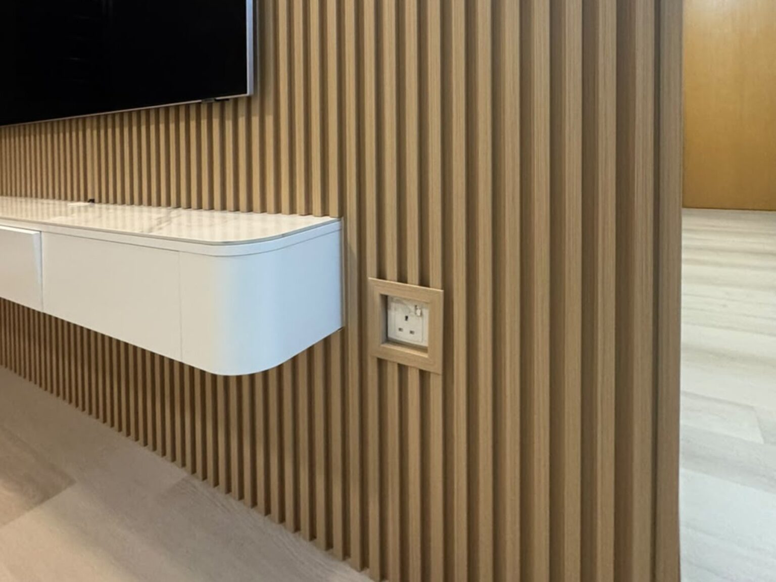 Close-up of a fluted panel TV wall with a recessed socket