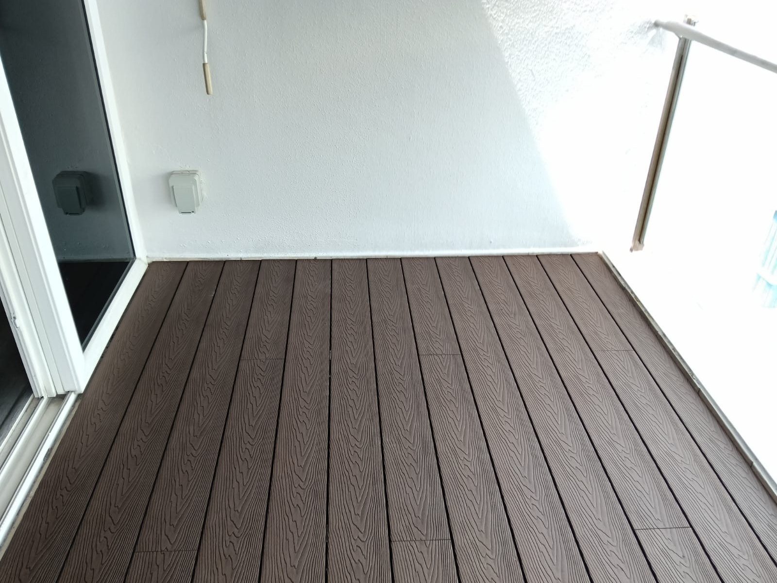 Composite decking laid to the edge of a glass-railed balcony