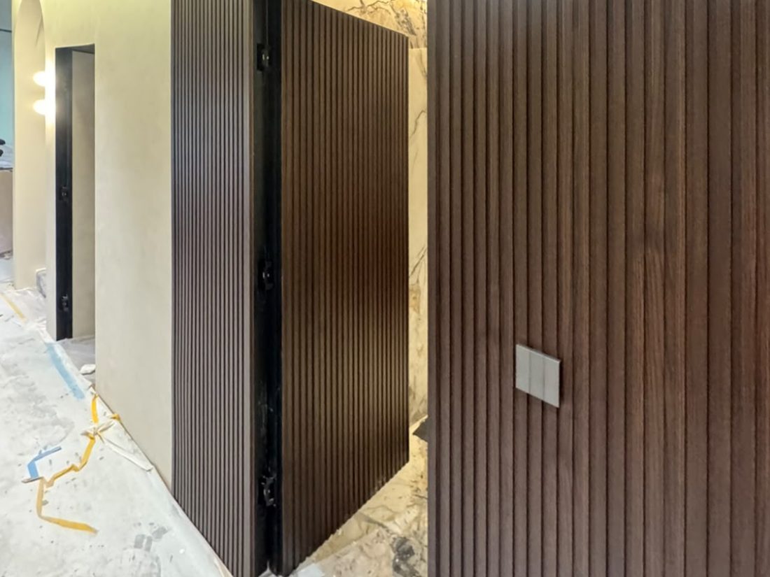 Dark Walnut fluted panels wrapping a corridor wall and concealed door
